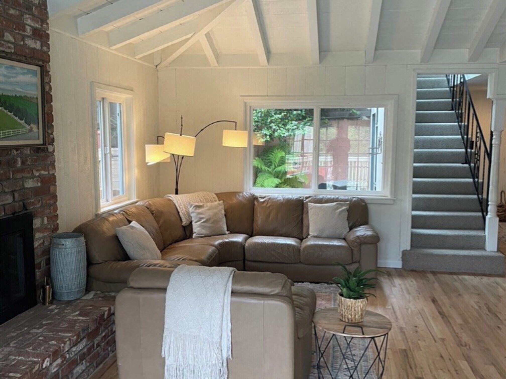 A cozy living room with a sectional sofa, a fireplace, and a staircase.
