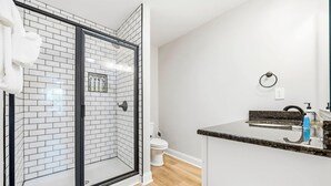 A modern bathroom with a glass shower enclosure, a white toilet, and a granite countertop sink. - Perfect Inlet Stay Minutes to MarshWalk & Water (Murrells Inlet)