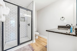 A modern bathroom with a glass shower enclosure, a white toilet, and a granite countertop sink. - Perfect Inlet Stay Minutes to MarshWalk & Water (Murrells Inlet)