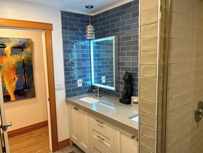 Um banheiro com toucador branco, espelho e parede revestida em azulejos azuis.