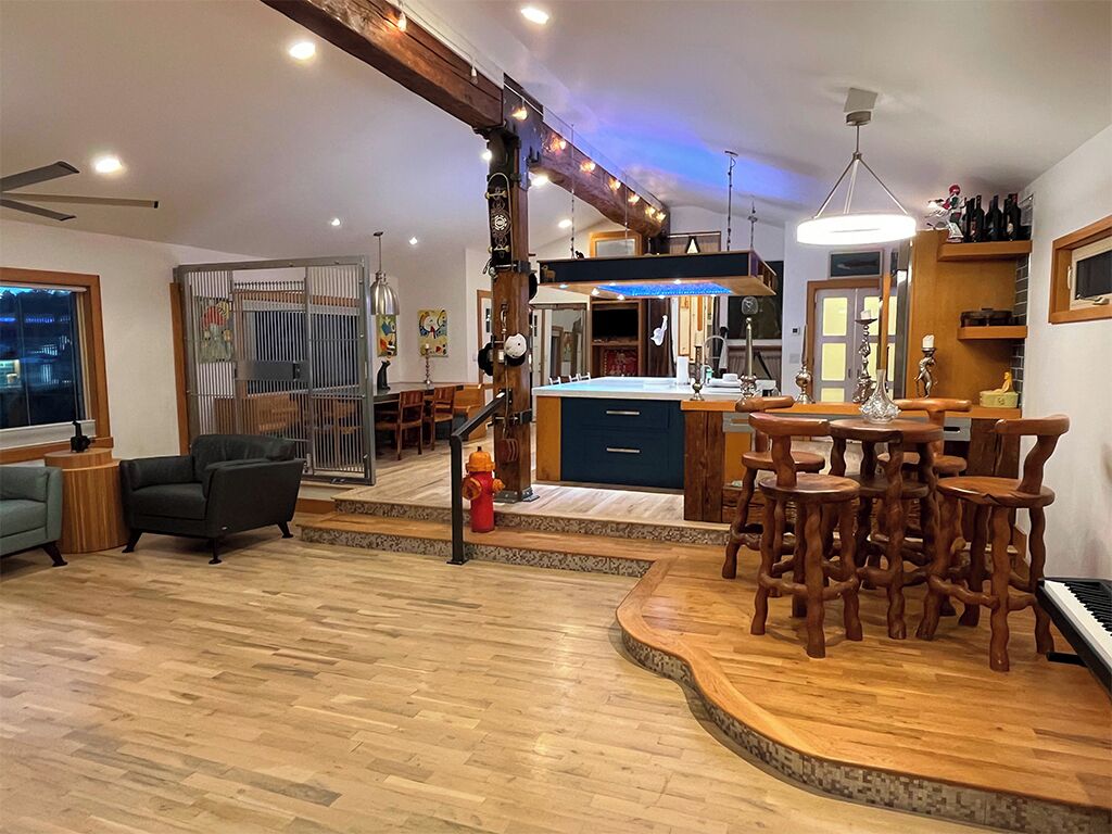 A modern kitchen with a central island, wooden bar seating, and a view of the city at night.