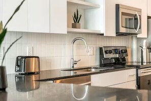 Une cuisine moderne dotée d’une cuisinière en acier inoxydable, d’un four à micro-ondes encastré et d’un plan de travail élégant.