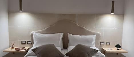 A modern hotel room with a large bed, two bedside tables, and a headboard.