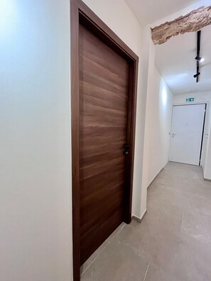En hall med en trädörr och en vit dörr längst ner.