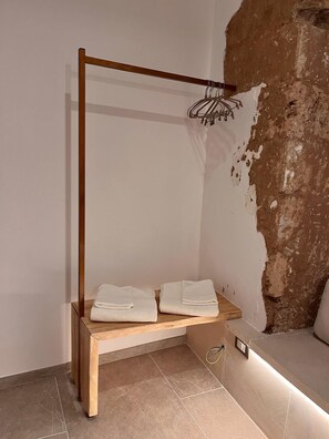 A room with a wooden bench, a hanging light fixture, and a stone wall. - Ada Vacation Home • 2 minutes from the ocean • Relaxation for Couples (Marina di Mancaversa)
