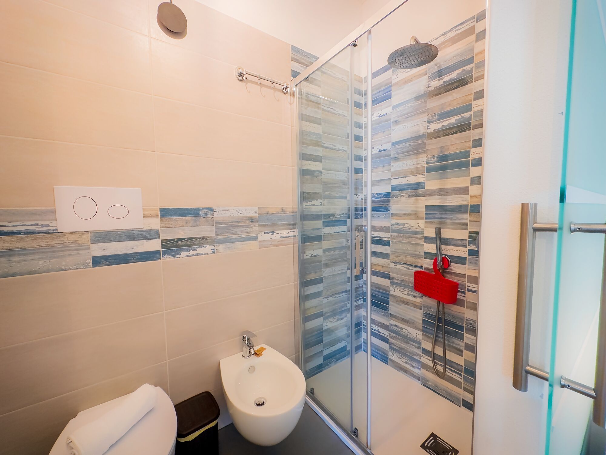 Ein modernes Badezimmer mit Duschkabine aus Glas, einem Bidet und einer Toilette.