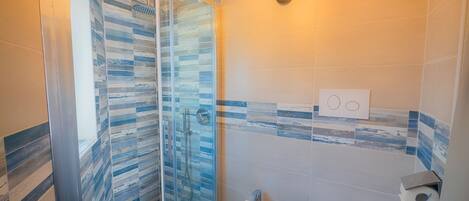 Ein Badezimmer mit Duschkabine aus Glas, einem Bidet und einer Toilette.