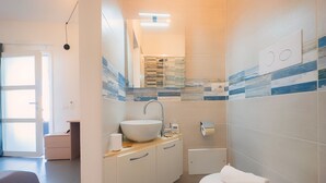 Casa de banho moderna com uma grande lavatório branco, sanita e zona de duche.