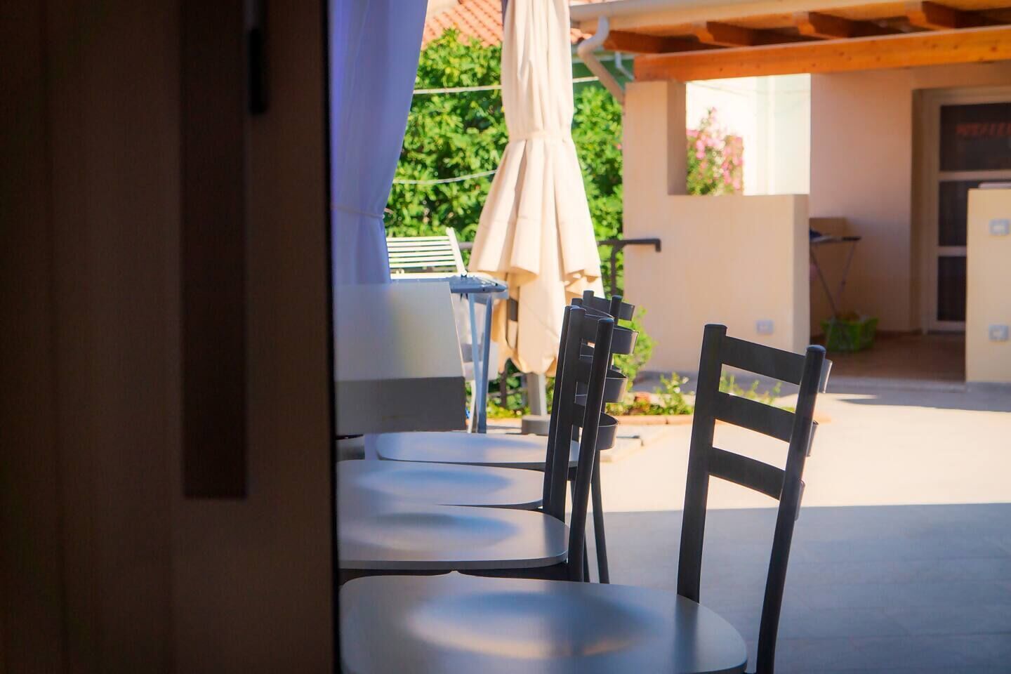 Un patio al aire libre con una mesa, sillas, una sombrilla y un edificio al fondo.