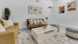A modern living room with a sofa, coffee table, and artwork on the walls. - The Sweet Home｜Central Located｜Perfect for Family (Las Vegas)