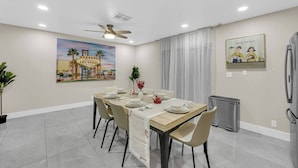 A dining area with a table set for four, a ceiling fan, and a painting of Las Vegas. - The Sweet Home｜Central Located｜Perfect for Family (Las Vegas)