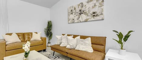 Ein modernes Wohnzimmer mit zwei Sofas, einem Couchtisch und einem Gemälde an der Wand.