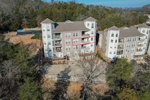 A multi-story residential building with balconies, a parking area, and a natural landscape in the background. - Lakeview Condo (Kimberling City)