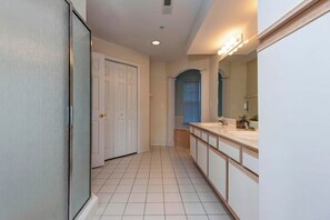 A bathroom with a large mirror, two sinks, and a door leading to another room. - Lakeview Condo (Kimberling City)