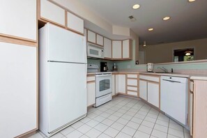 A modern kitchen with white appliances, wooden cabinets, and a tiled floor. - Lakeview Condo (Kimberling City)
