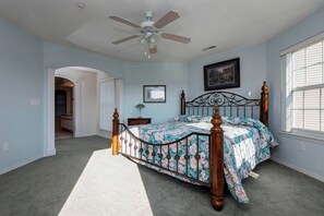 A bedroom with a bed, a ceiling fan, a nightstand, a framed picture, and a window. - Lakeview Condo (Kimberling City)