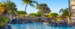 A pool with a waterfall feature surrounded by palm trees and lounge chairs. - 2-bedroom condo in tranquil Maui perfect for relaxing getaways (Maui)