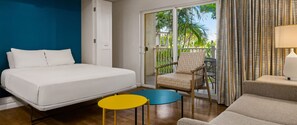 A hotel room with a bed, a chair, a small table, a sofa, and a balcony with curtains. - 2-bedroom condo in tranquil Maui perfect for relaxing getaways (Maui)