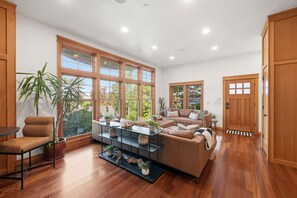 Ein geräumiges Wohnzimmer mit großem Fenster, einer Couch, einem Couchtisch und einem Sessel.