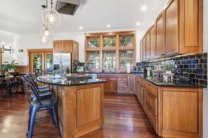 A spacious kitchen with wooden cabinets, a large island, and a dining area with chairs. - Luxury Iconic Fairmount Blvd UO Campus House (Eugene)