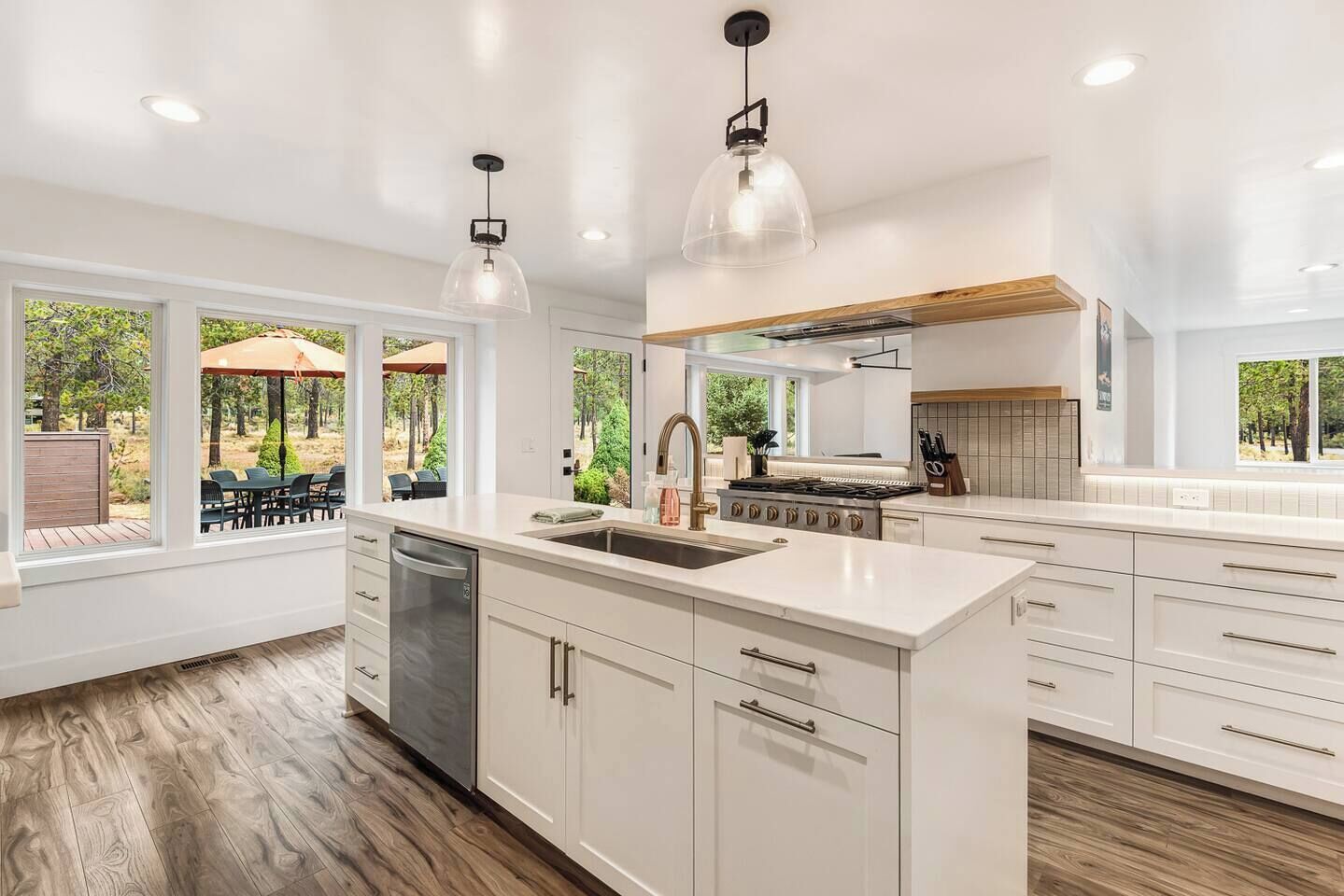 Una cocina amplia con armarios blancos, una isla central y vista a un patio exterior.