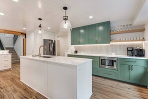 A modern kitchen with a central island, stainless steel appliances, and green cabinets. - On Golf Course, Walk to Park, Hot tub, SHARC (Sunriver)