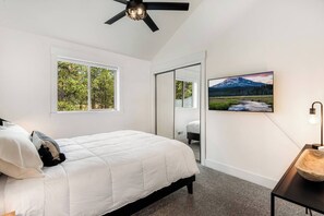 Ein Schlafzimmer mit Bett, Deckenventilator, Fenster, Tür und einem Wandbild.