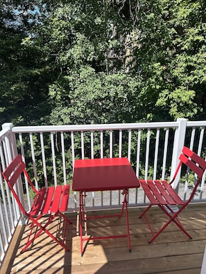A wooden deck with a white railing and red furniture, including a table and two chairs. - Chez Rose Charming Knowlton Retreat -Walk to Cafés and Shops (Lac-Brome)