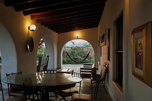 Une terrasse couverte avec une table et des chaises, un hamac et une vue sur la verdure et les montagnes.