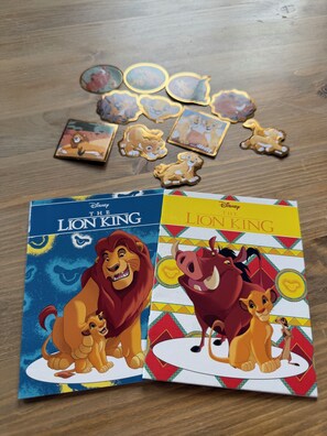 Un jeu de société intitulé « Le Roi Lion de Disney », avec sa boîte et ses pièces, est posé sur une surface en bois.