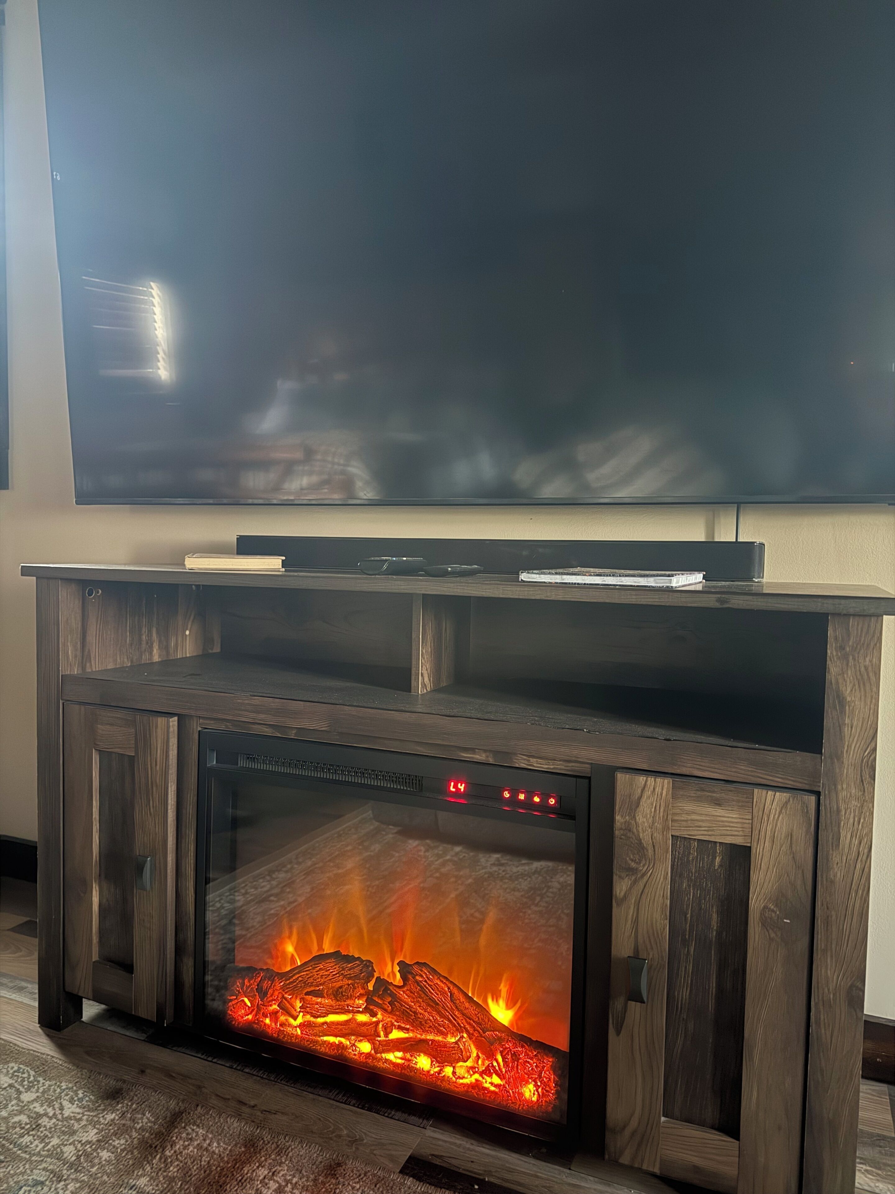 A fireplace with a TV above it, a clock, and a book on the mantel.