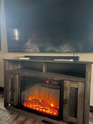 Una chimenea con un televisor encima, un reloj y un libro en la repisa.