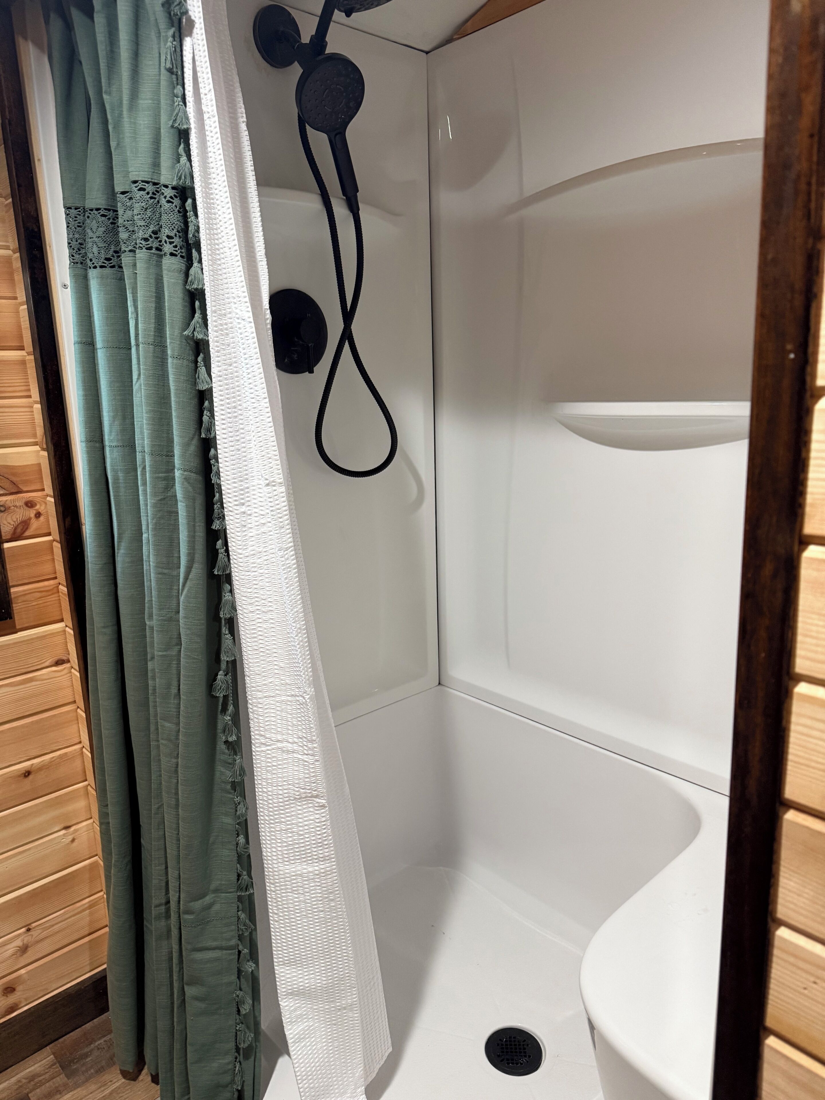 A shower area with a white sink, a showerhead, and a curtain.
