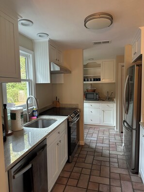 A kitchen with white cabinets, a stainless steel refrigerator, a microwave, and a stove. - Heart of the Bay! Charming 3-bedroom house with AC, walk to the beach. (Mashpee)