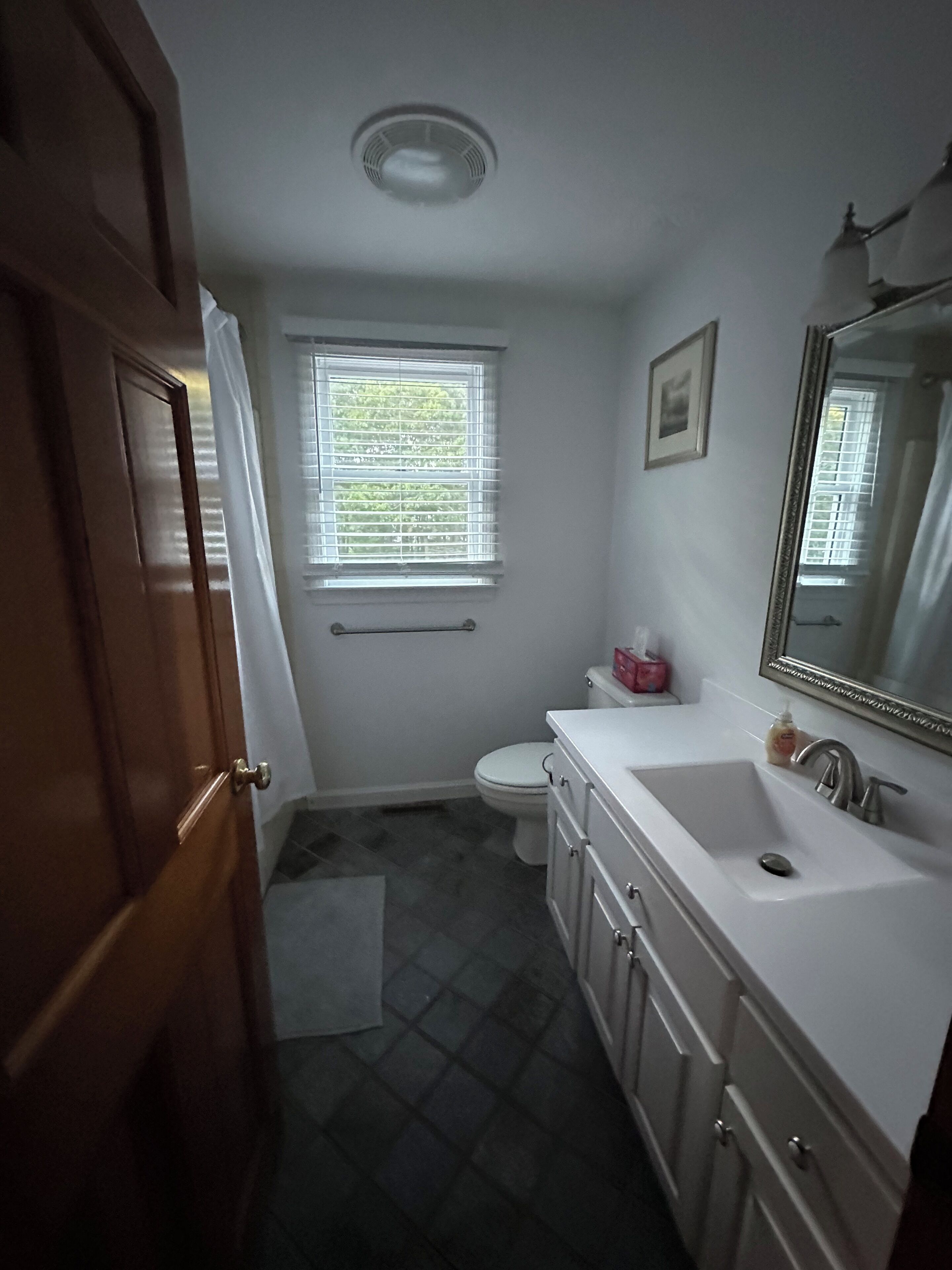 A bathroom with a toilet, sink, and mirror.