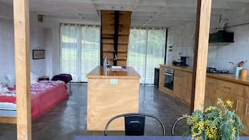 Una stanza con un letto, un angolo cottura e un tavolo da pranzo con un vaso di fiori.