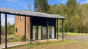 Uma casa moderna com varanda coberta e uma estrutura de madeira isolada.