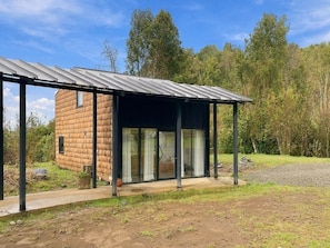 A modern house with a covered porch and a separate wooden structure.