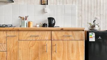 Uma cozinha com armários de madeira, uma geladeira preta e uma cafeteira no balcão.