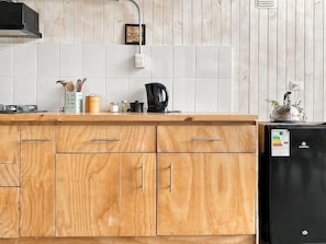 A kitchen with wooden cabinets, a black refrigerator, and a coffee maker on the counter.