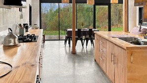A modern kitchen with a wooden countertop, a dining table, and a view of the outdoors.