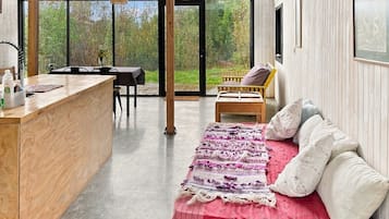 Interior moderno com balcão de madeira, cama vermelha com almofadas e vista para o exterior.