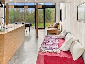 A modern interior with a wooden bar, a red bed with pillows, and a view of the outdoors.