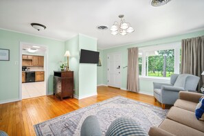 Un salon doté d’un téléviseur à écran plat, d’un meuble en bois, d’un tapis à motifs et offrant une vue sur l’extérieur par une fenêtre.