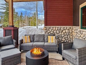 An outdoor seating area with a stone wall, a fire pit, and a view of a snowy landscape. - Aspen View Lodge | Hot Tub & Game Room (Breckenridge)