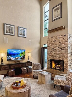 A spacious living room with a fireplace, comfortable seating, a flat-screen TV, and artwork on the walls. - Aspen View Lodge | Hot Tub & Game Room (Breckenridge)