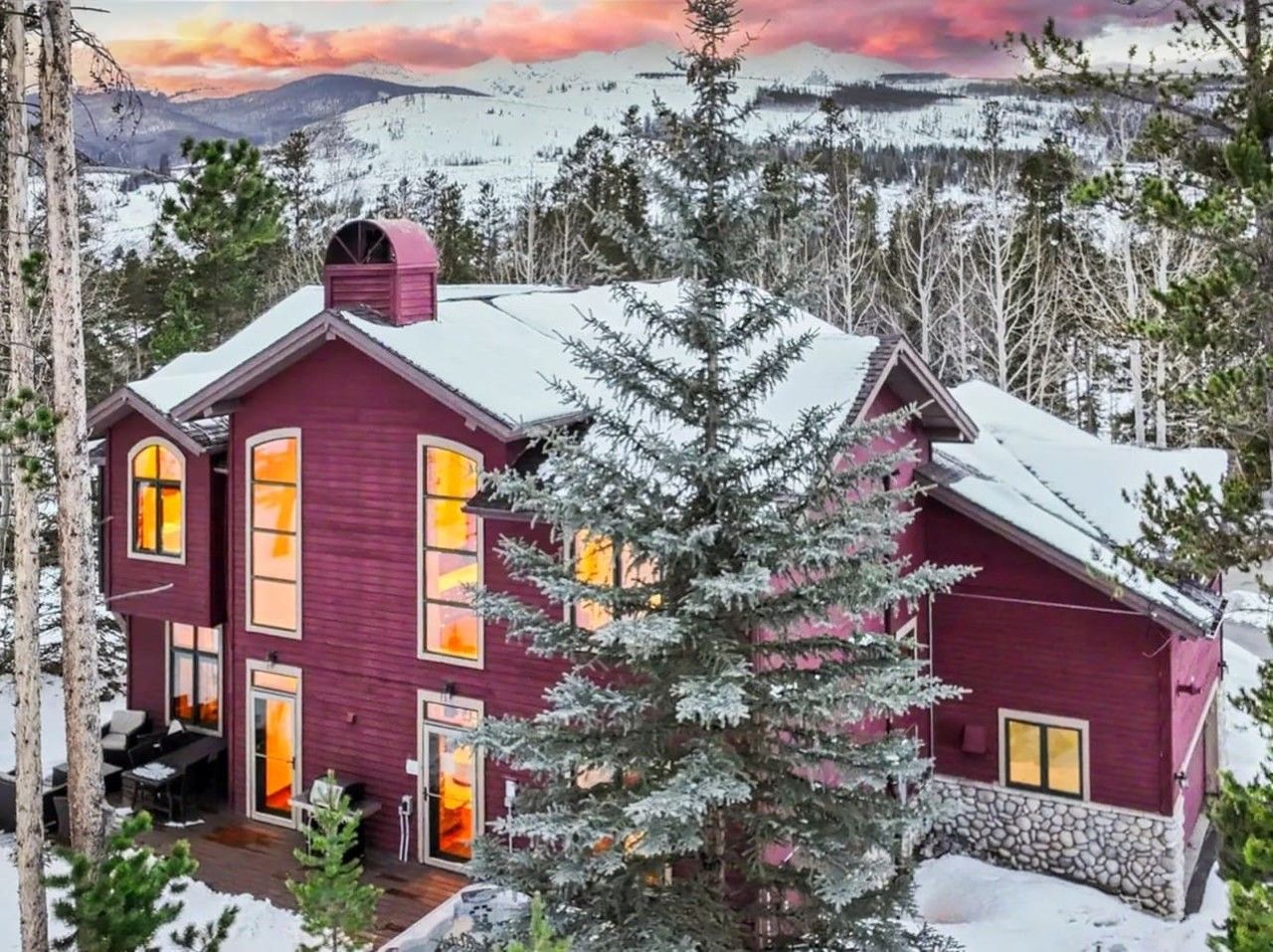 A large, two-story house with a red exterior, multiple windows, and a snow-covered roof.