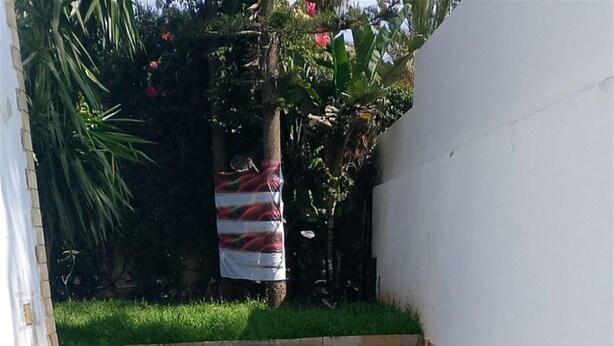 Une piscine avec un escalier en métal qui y mène, entourée d’une terrasse carrelée et d’un mur blanc.