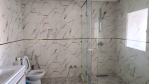 Une salle de bain avec une douche à parois de verre, des toilettes et un lavabo.
