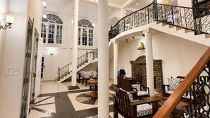 A spacious lobby with a grand staircase, high ceilings, and classical architectural details.